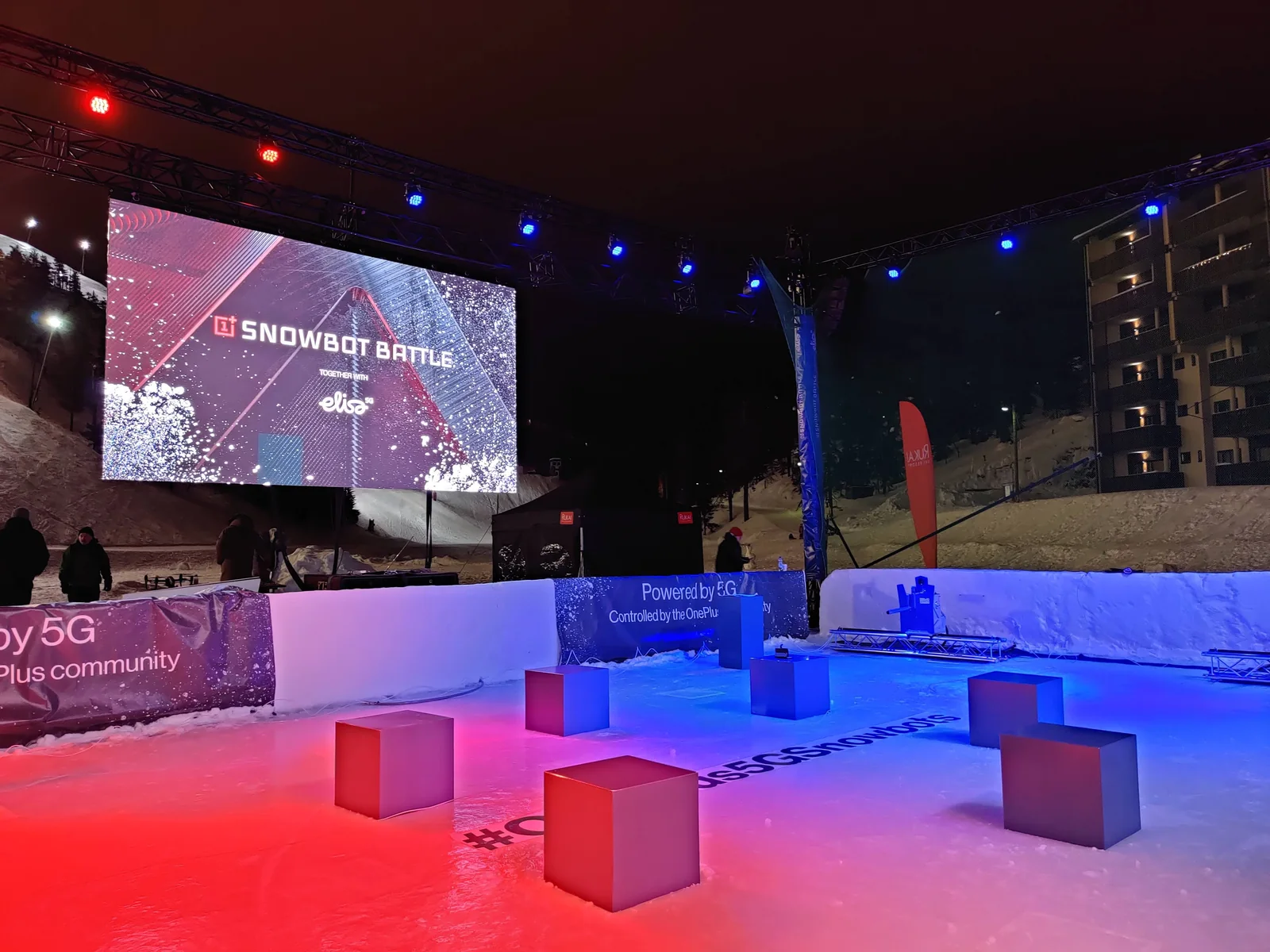 The OnePlus 5G Snowbot Battle arena lit up at night in Ruka, Finland