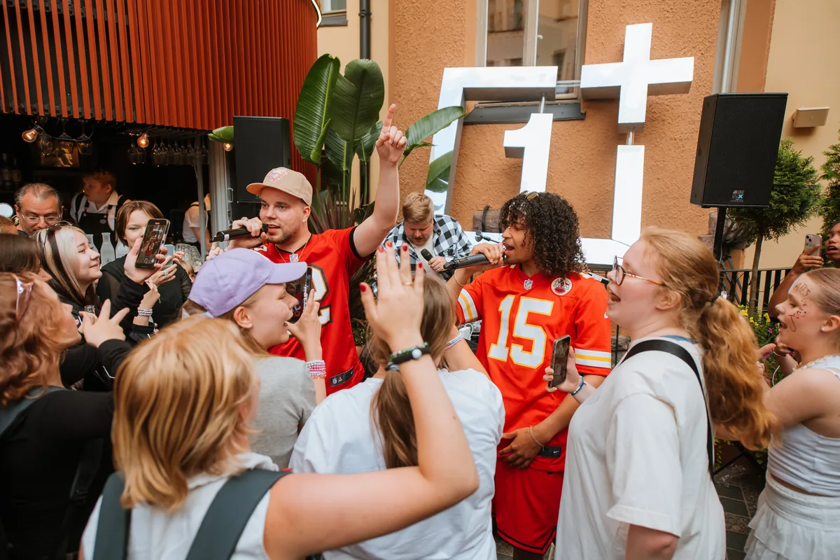 Rappers performing to a crowd in front of the OnePlus logo at the Helsinki pop-up