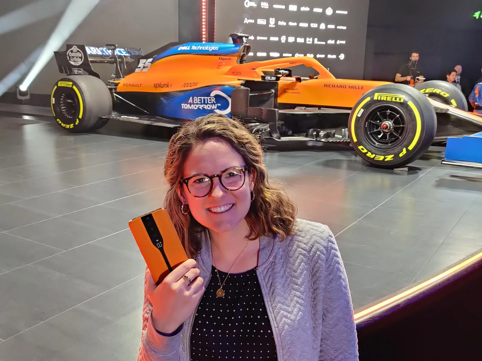 Kate holding the OnePlus Concept One in front of a McLaren F1 car