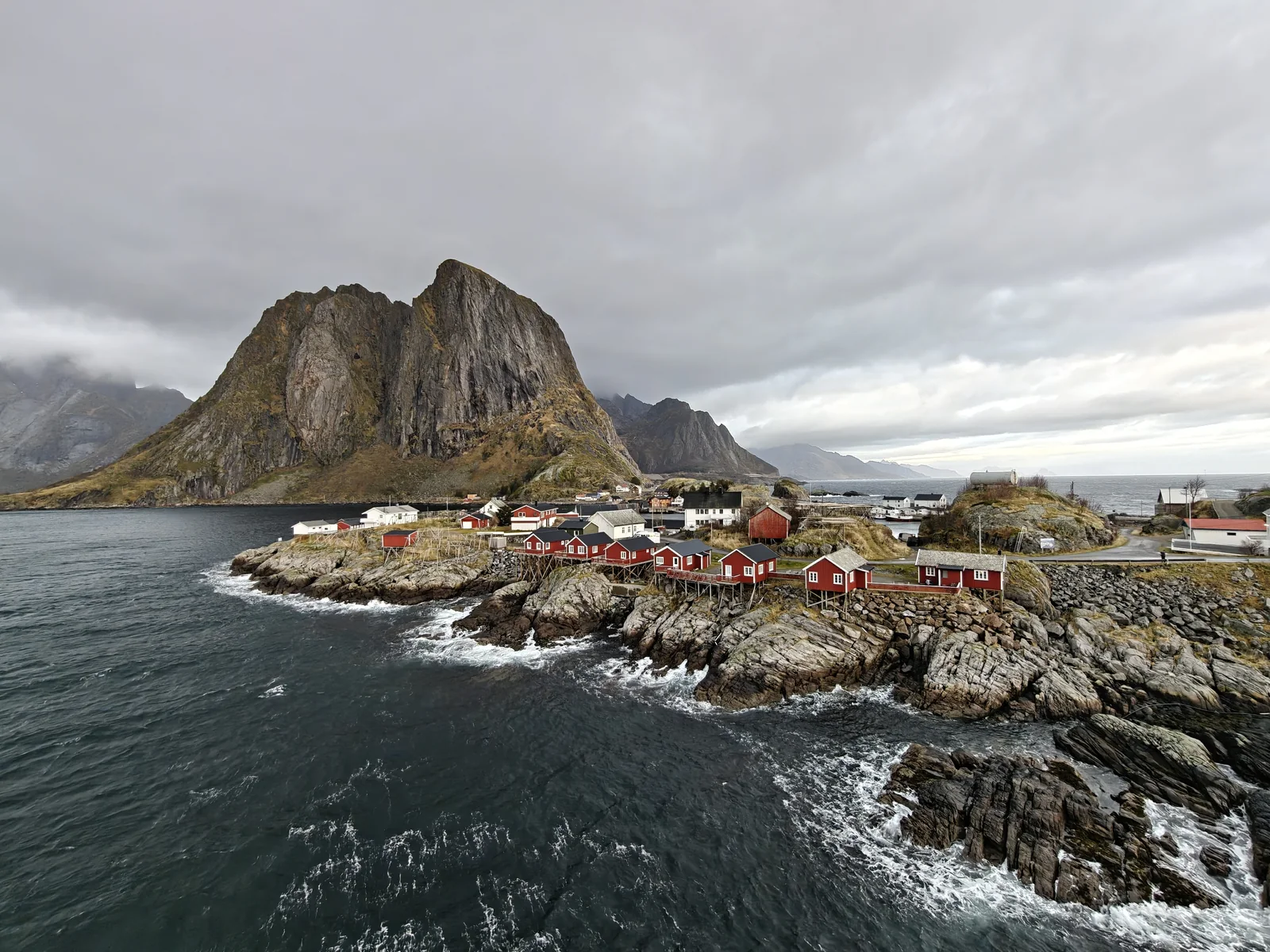 Red fishing cabins beneath a mountain in Lofoten, shot on OnePlus