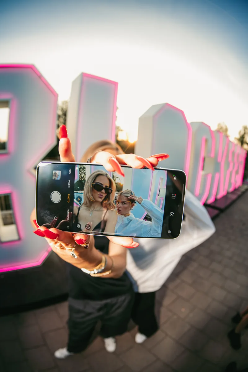 Friends taking a selfie on a OnePlus phone in front of the Blockfest sign