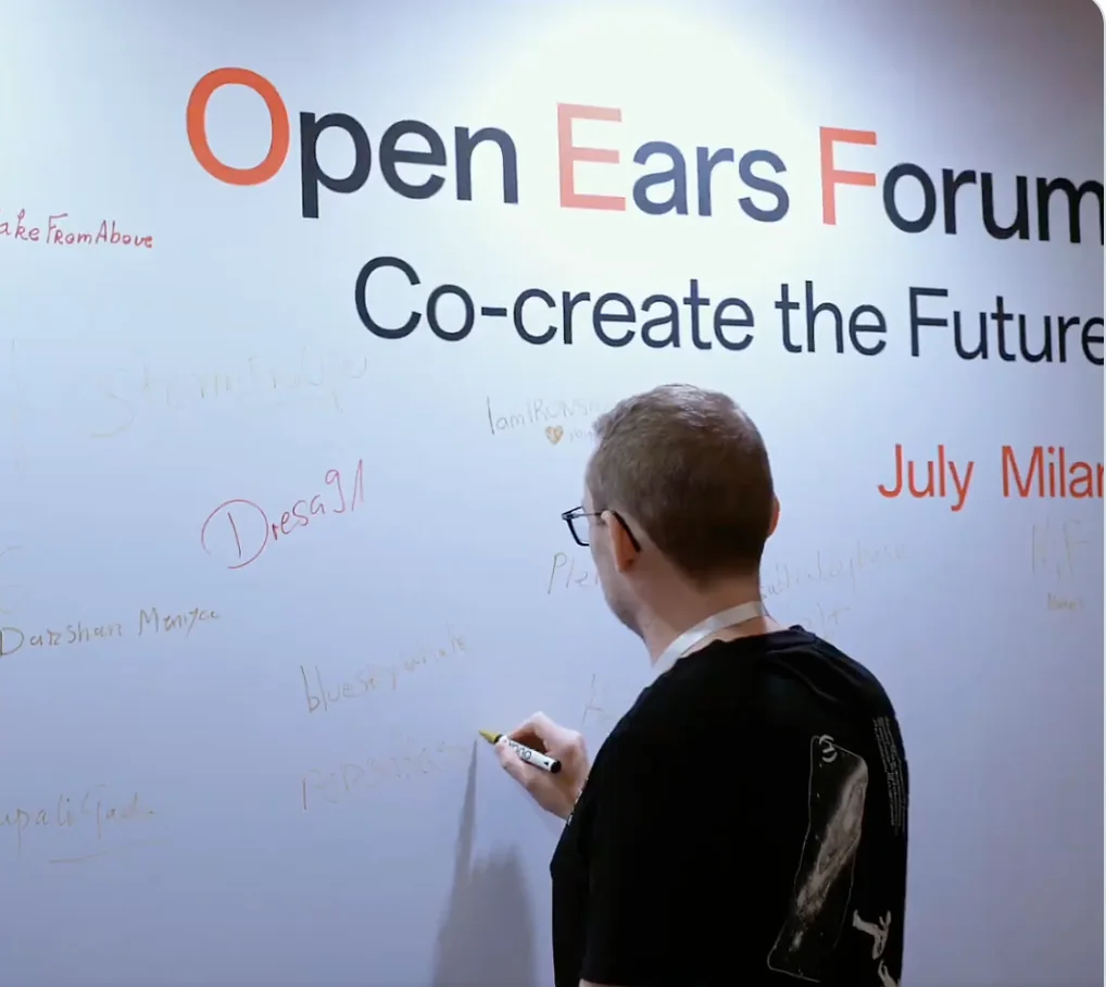 A community member signing the Open Ears Forum wall